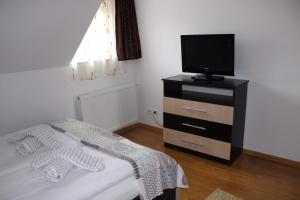 a bedroom with a bed and a television on a dresser at Napsugár Vendégház in Sovata