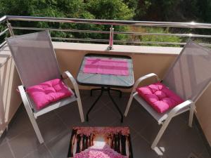 - un balcon avec 2 chaises et une table et des oreillers roses dans l'établissement Marina, à Budva