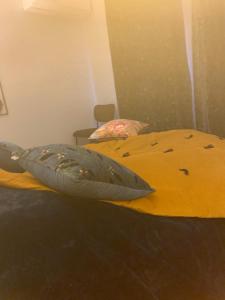 a bed with a yellow comforter and a pillow at coeur de ville t2, terrasse, clim tt équipe, parking in Sanary-sur-Mer