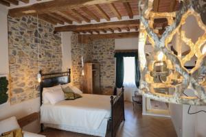 sypialnia z łóżkiem i kamienną ścianą w obiekcie B&B La Taccola w mieście Castelnuovo di Val di Cecina