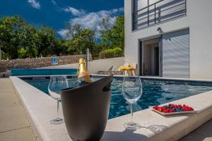 een fles champagne en wijnglazen naast een zwembad bij Apartment Di Blu in Novi Vinodolski