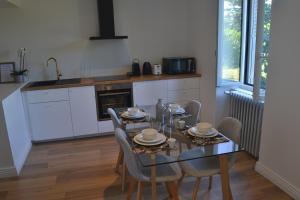 une salle à manger avec une table et des chaises ainsi qu'une cuisine dans l'établissement Le Bompard 50 m2 Villa Art Déco Plein centre avec jardin, à Rodez
