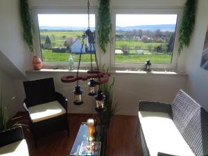 a living room with two chairs and a table and two windows at Ferienwohnung Kapust in Hessisch Oldendorf