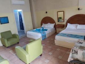 une chambre d'hôtel avec deux lits et une chaise dans l'établissement Grand Bay Beach Tourist Residence Mauritius, à Grand Baie