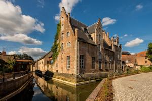 an old brick building next to a canal in a city at Oranje City Hotel in Diest