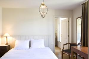 a bedroom with a white bed and a desk and a lamp at Oranje City Hotel in Diest
