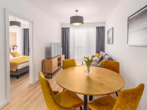 a living room with a table and chairs and a bedroom at FARO Apartamenty Kasprowicza 20 in Kołobrzeg