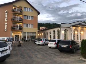 a parking lot in front of a building with cars parked at Hotel-Restaurant Oscar in Piatra Neamţ