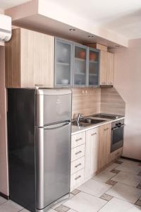 RogachevoにあるLa Mer Apartmentのキッチン(ステンレス製の冷蔵庫、木製キャビネット付)