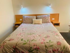 1 dormitorio con 1 cama con colcha de flores en Anna Bella Motel Glen Innes, en Glen Innes