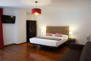 a bedroom with a white bed with pink pillows at Fonda Biayna in Bellver de Cerdanya 