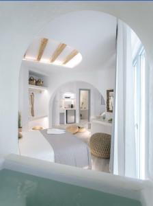 a white room with a bed and a swimming pool at Majestique of Naxos in Naxos Chora