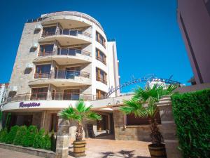 a tall building with palm trees in front of it at Magnolia Garden in Sunny Beach