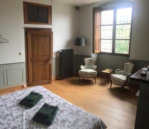 a bedroom with a bed and chairs and a window at La Prévôté in Marchenoir