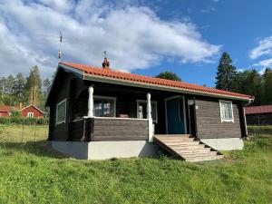 ein kleines schwarzes Haus mit einer Veranda und einer Veranda in der Unterkunft Vasa Ski Lodge in Mora