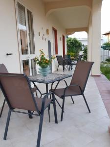 una mesa de patio con sillas y un jarrón de flores en Confetti di Mandorla beach house, en Avola