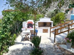 a garden with a white house with a stove at Sylvia's houses in Kalymnos