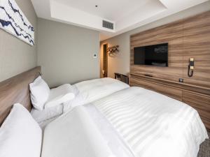 a bedroom with a large white bed and a flat screen tv at Far East Village Hotel Tokyo Ariake in Tokyo