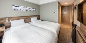 a large white bed in a room with a television at Far East Village Hotel Tokyo Ariake in Tokyo