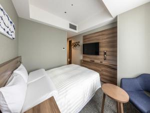 a hotel room with a bed and a blue chair at Far East Village Hotel Tokyo Ariake in Tokyo