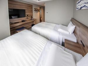 a hotel room with two beds and a television at Far East Village Hotel Tokyo Ariake in Tokyo