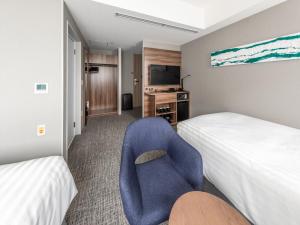 a hotel room with two beds and a blue chair at Far East Village Hotel Tokyo Ariake in Tokyo