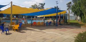 a blue and yellow tent with chairs and a pool at Kibbutz Nachshon in Kibbutz Nachshon