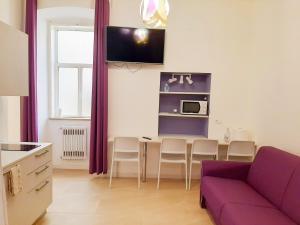 a living room with a purple couch and a table at Trieste Center Rooms & Apartments - Fiori di Trieste in Trieste