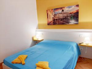 a bedroom with a blue bed with yellow towels on it at Trieste Center Rooms & Apartments - Fiori di Trieste in Trieste
