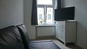 ein Schlafzimmer mit einem TV auf einer Kommode mit einem Fenster in der Unterkunft Pension am Aubach Schwerin in Schwerin