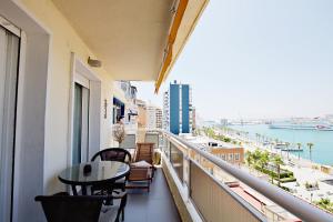 balcón con mesa, sillas y vistas al agua en La Marina Suite Málaga, en Málaga