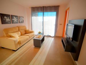 a living room with a couch and a television at Apartamentos Bravosol VyB in Denia