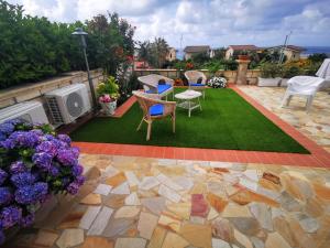 a backyard with a lawn with chairs and a table at Casa Vacanze Villa Mimosa- per le vacanze vicino a Tropea in Briatico