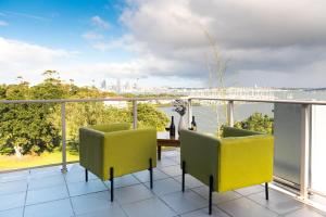 a balcony with yellow chairs and a table with a view at Ocean Breeze Hotel in Auckland