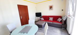 ein Wohnzimmer mit einem roten Sofa und einem Tisch in der Unterkunft Apartmani Zorzo in Ljubač
