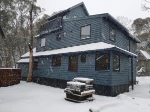 a blue house with snow on it in the yard at SNOWED INN apartment in Dinner Plain