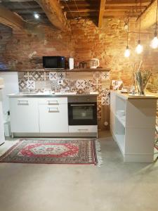 a kitchen with white appliances and a brick wall at L' Atelier Tuscany in Peccioli