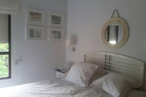 - une chambre blanche avec un lit et un miroir dans l'établissement Santiago de la Ribera, à San Javier