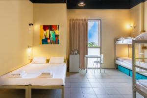 a bedroom with two beds and a window and a table at Abraham Tel Aviv in Tel Aviv