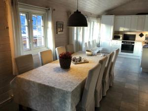 a dining room with a table with chairs and a kitchen at Sørlia hytte in Hafjell