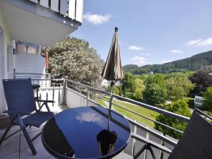 a patio with a table and an umbrella on a balcony at Ferienwohnung M am Kurpark**** inkl. MeineCard+ in Willingen