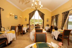 a restaurant with tables and chairs and a chandelier at The 19th Golf Lodge in Ballybunion