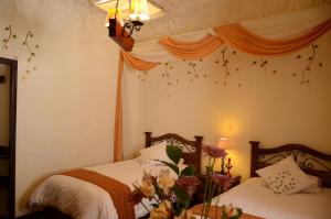 a bedroom with two beds and flowers on the wall at Unaytambo Boutique Hotel Cusco in Cusco