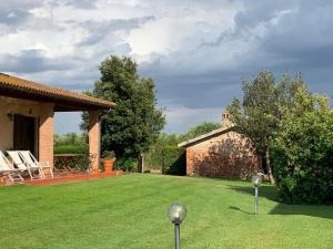 a yard with a brick house and a lawn with chairs at Agriturismo Beveraggio Appartamenti in Marina di Grosseto