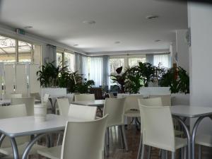 ein Restaurant mit weißen Tischen und Stühlen und Pflanzen in der Unterkunft Hotel Haiti in Milano Marittima