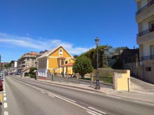 una casa gialla sul lato di una strada di Casa Marisma Xacobeo a Sanxenxo