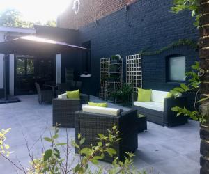 d'une terrasse avec des meubles en osier et un mur en briques. dans l'établissement La Villa des Roses - Suite & Spa, à Lys-lès-Lannoy