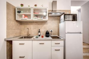 La cuisine est équipée de placards blancs et d'un réfrigérateur blanc. dans l'établissement Novembre 152 Apartment, à Rome