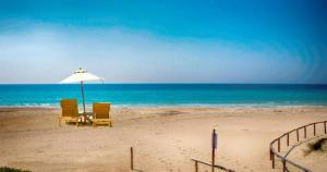 duas cadeiras e um guarda-sol numa praia em Hotel Aurora em Porto Cesareo