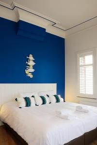 - une chambre avec un grand lit blanc et un mur bleu dans l'établissement De Kaai, à Halle